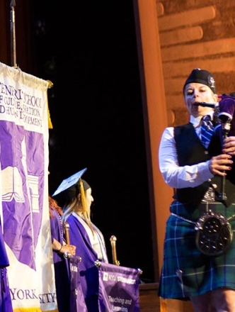 Graduating students on stage with banners and bag pipe players