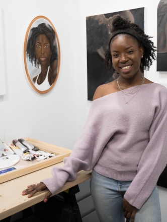 BFA student in studio with paintings.