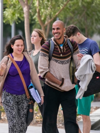 A diverse group of students walk through Washington Square park