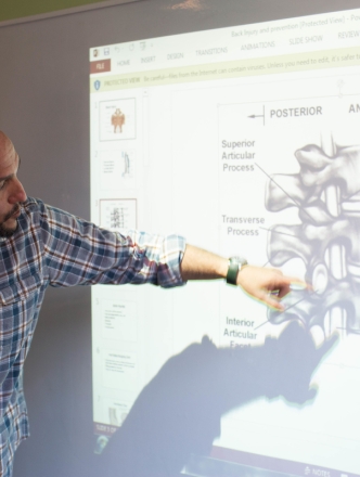faculty member pointing to a projection screen of a closeup on the spine