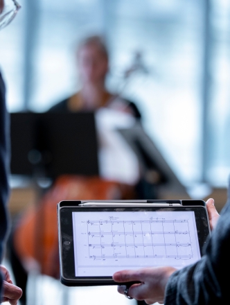 two individuals looking at sheet music on an iPad
