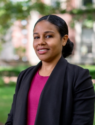 Stationary shot of Professor Brittany Fox-Williams outside on campus in a pink shirt and black blazer. 