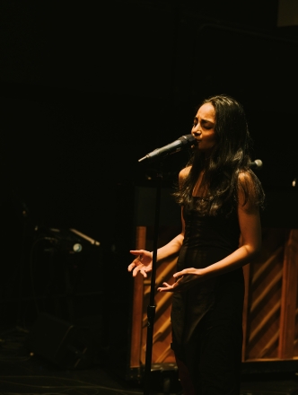 Student singing on stage in front of piano