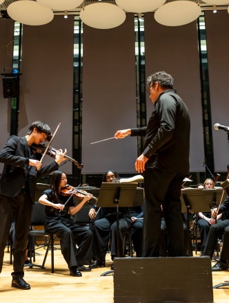 Symphony performing while conductor points to soloist violin player