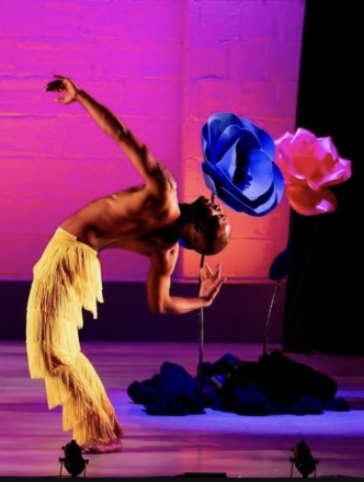 Dancer doing backbend in front of large flowers with pink background