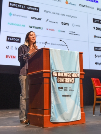Student at podium with a list of music vendors behind her 