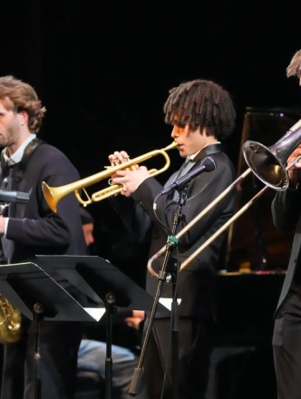 Three jazz musicians on stage performing their horn instruments
