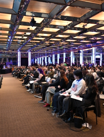 Professor at the podium in front of large audience of students and faculty