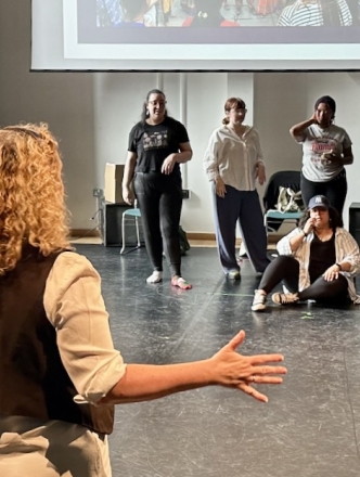 Professor working with theatre students in large room. Learning movements.