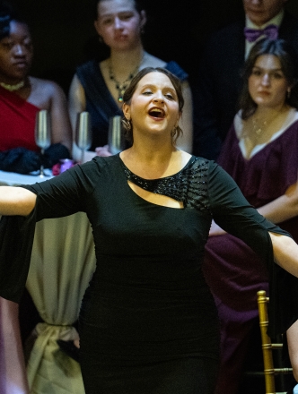 Opera singer in front of actors sitting at cafe style tables