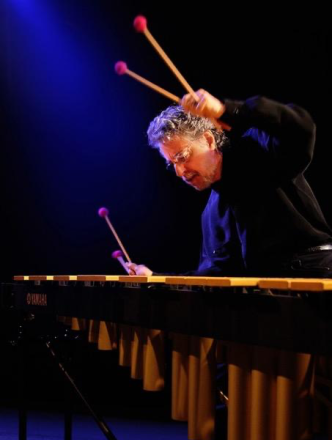 Professor playing long percussion instrument with four sticks