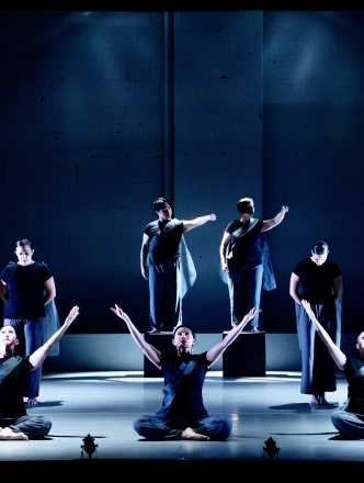 A deep blue stage with dancers posed, some on the floor and some standing