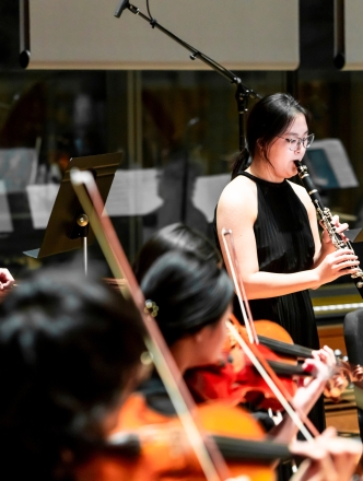 Students performing with clarinet player being featured standing up