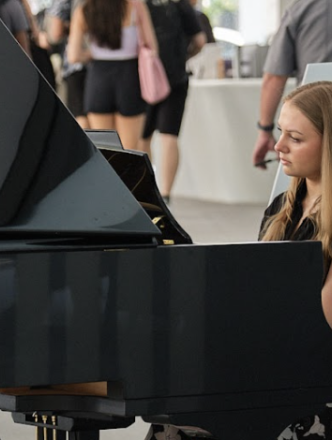 A woman plays piano on stage.