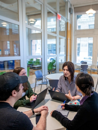 Four students sitting around a table in Pless lounge. 
