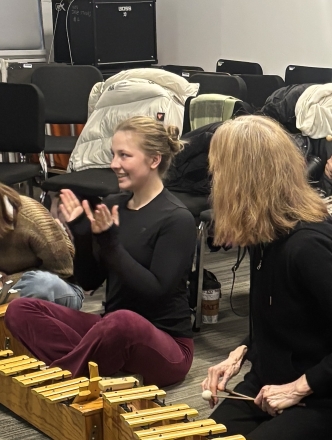 Six students sitting on the floor playing instruments
