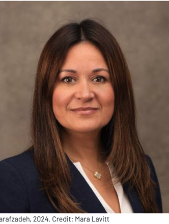 A woman with tan skin and long brown hair looks into the camera.