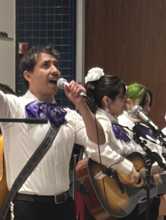 Mariachi performing with lead singer lifting one arm up in the air in celebration