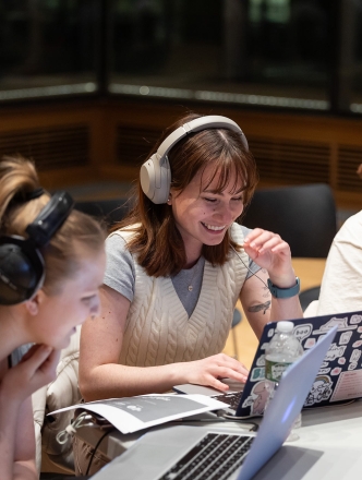 students sitting around a table with headphones and laptops open
